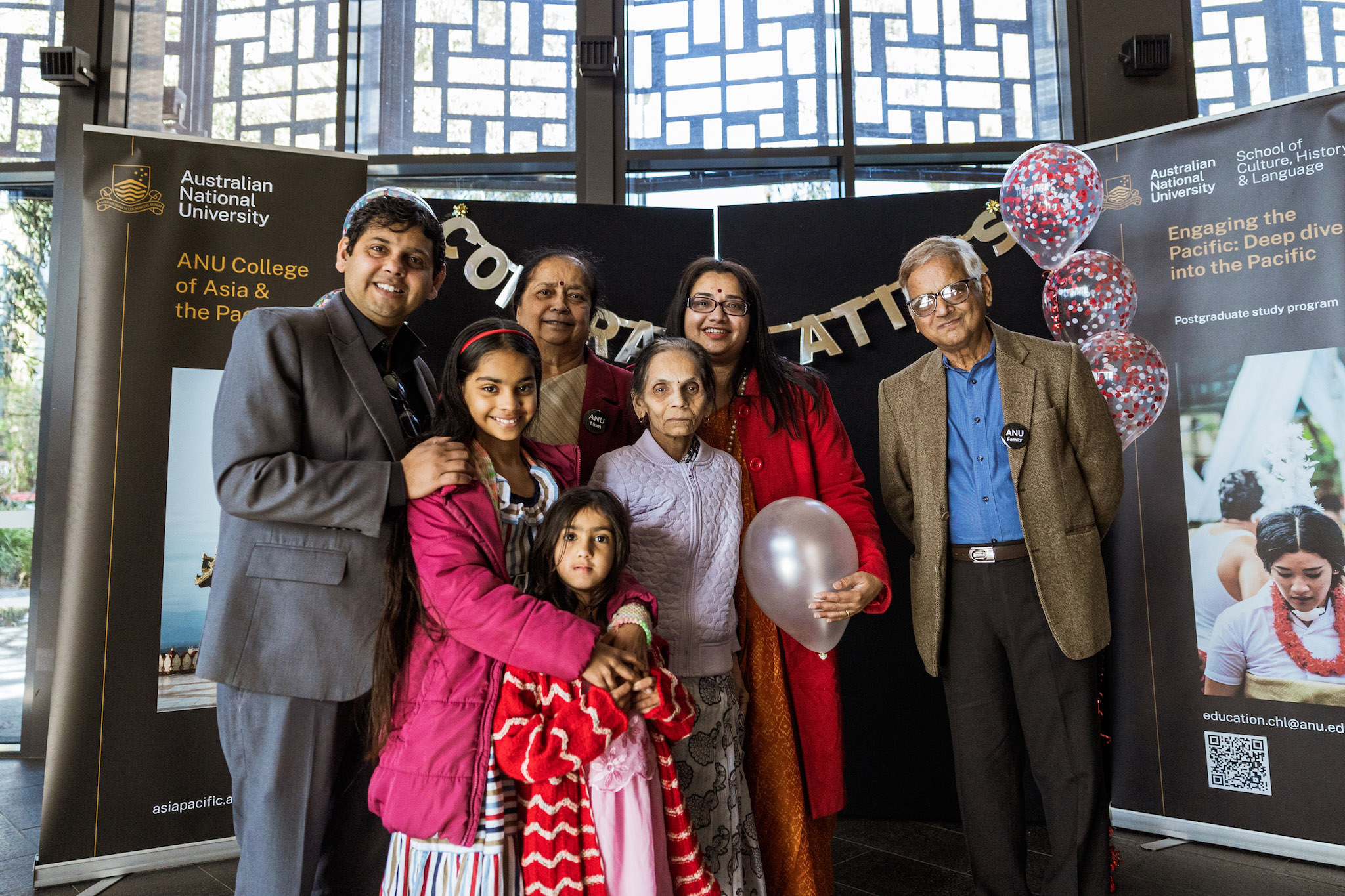 A family celebrating at the School of Culture, History and Language post-graduation get together A family standing in front of banners for the School of Culture, History and Language