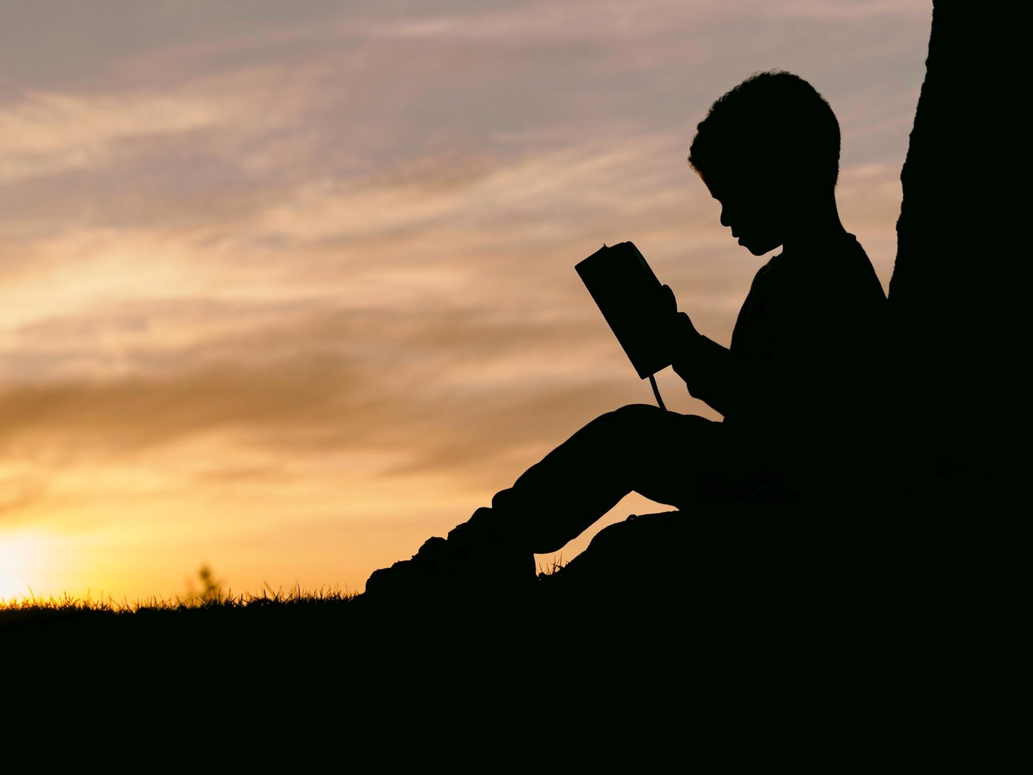 Silhoette of a boy reading a book