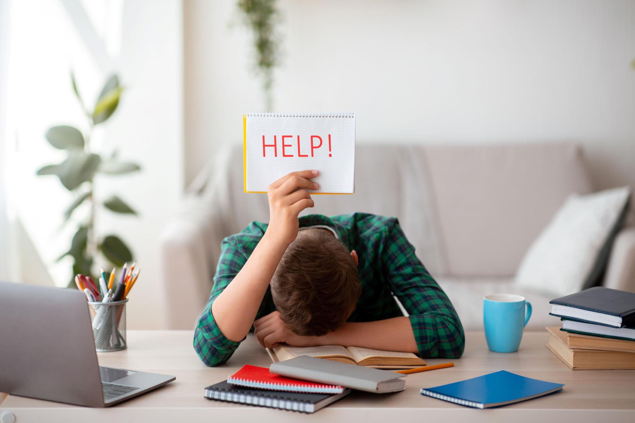 man slumped on desk with help sign