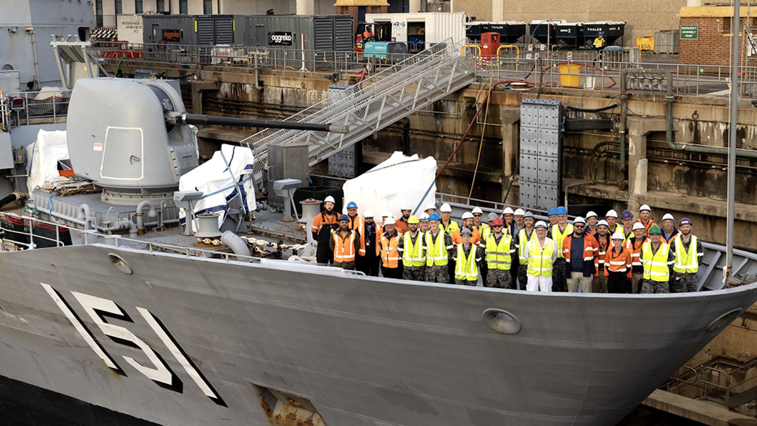 Large Royal Australian Navy ship, with shipbuilders on the prow
